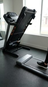 Compact folding treadmill shown next to a slimmer walking pad for size comparison.